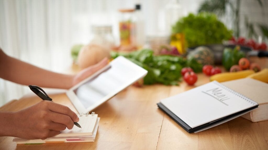 A calm workspace with an open notebook, fresh vegetables, and planning materials representing a thoughtful approach to nutrition education